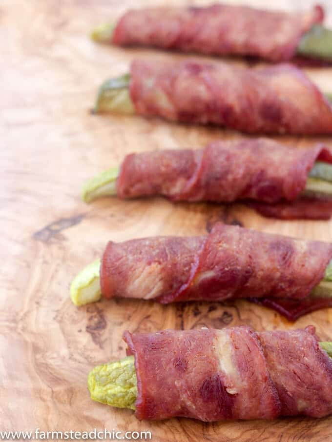 Bacon-wrapped pickles on a natural wood cutting board
