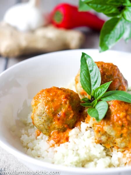 Low Carb, Keto Curry Turkey Meatballs served over cauliflower rice and topped with red curry sauce and fresh Thai basil