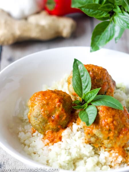 Low Carb, Keto Curry Turkey Meatballs served over cauliflower rice and topped with red curry sauce and fresh Thai basil