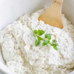 These Low Carb, Keto Mashed Cauliflower Fauxtatoes are super creamy and flavored with plenty of butter, thyme, oregano and garlic. Enjoy them at your next holiday gathering or summer BBQ. They taste like the best-ever garlic herb mashed potatoes with only a fraction of the carbs! #farmsteadchic #ketopotatoes #keto #lowcarb #lowcarbpotatoes #mashedpotatoes #mashedfauxtatoes #fauxtatoes #holidaysidedish #holidaysidedishes #ketosidedish #lowcarbsidedish